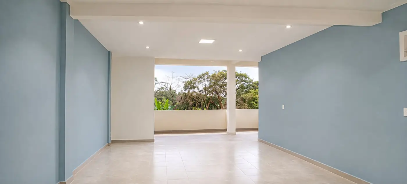 Living integrado pintado en azul acero con balcón y vista al jardín