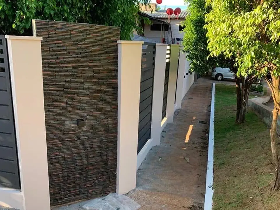 Muro perimetral con revestimiento en piedra y columnas pintadas, foto tomada por el cliente Elías López